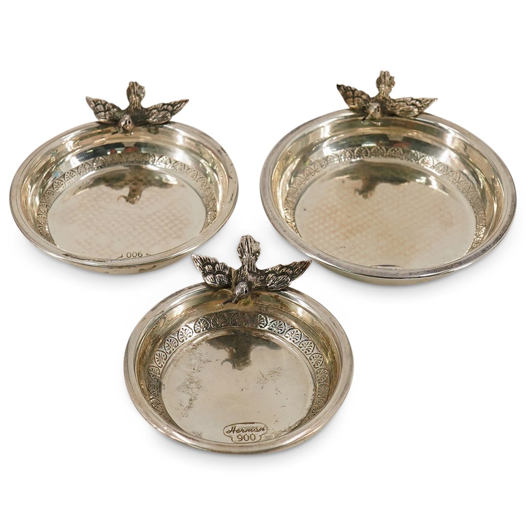 (3 Pc) Herman 900 Silver Figural Bird Dishes: DESCRIPTION: A set of (3) 900 silver dishes by Herman, each decorated with a dove holding an olive branch, graduating in size so each dish fits within each other. Stamped along the inner bowl "900" "H