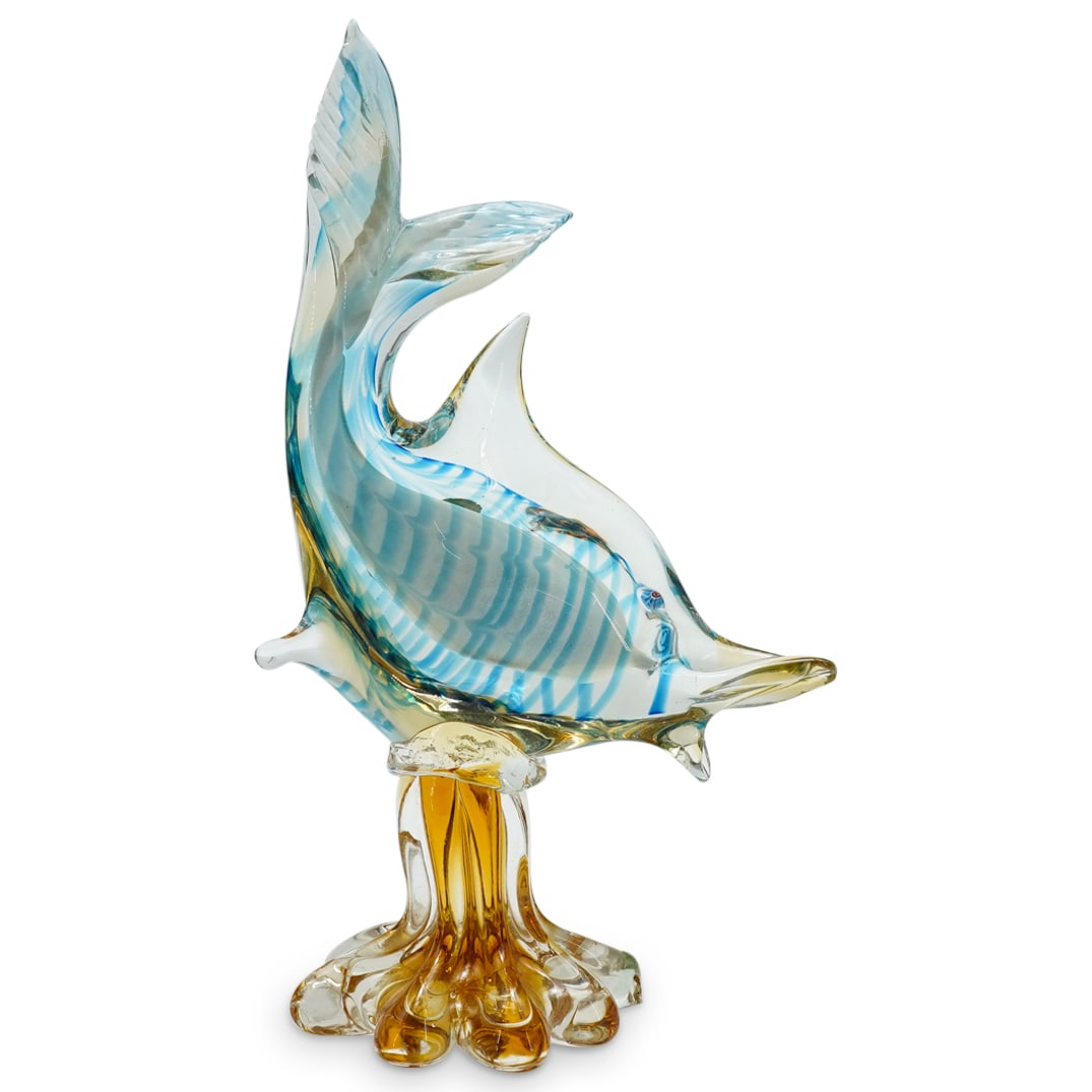 Murano Glass Fish On Water Spout: DESCRIPTION: Murano glass sculpture depicting a fish featuring a white center wrapped in translucent blue within a clear body sporting a millefiori eye and mounted on an amber tone water spout. CIRCA: