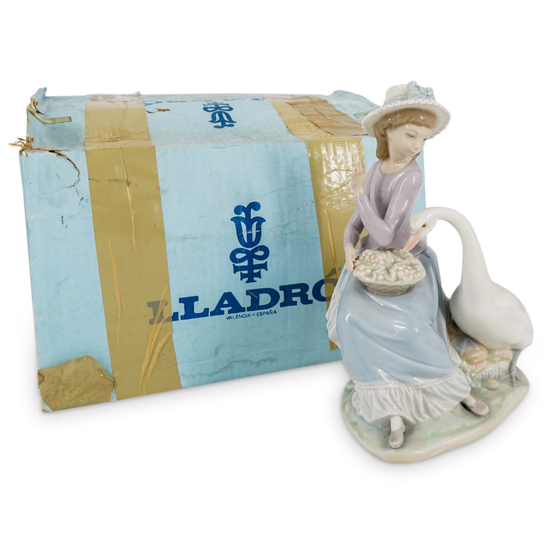 Lladro Porcelain "Goose Trying To Eat" Figurine: DESCRIPTION: Lladro porcelain figurine titled "Goose Trying To Eat", by designer Vicente Martinez. Spanish Name: "Oca Golosa". Depicts a young girl and a goose. Issued in 1979 and retired in 1996. Mod