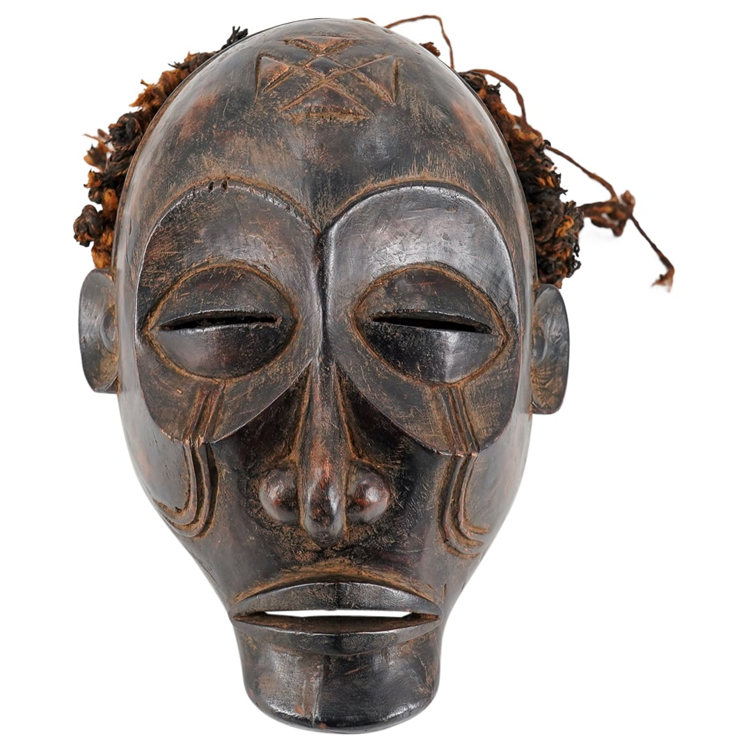 Chokwe Mwano Pwo Carved Wood Mask: DESCRIPTION: Carved wood Chokwe mwano pwo mask sporting exaggerated features, tribal marks on the cheeks, a geometric mark on the forehead, and braided hair. CIRCA: 20th Century ORIGIN: Central / Sout