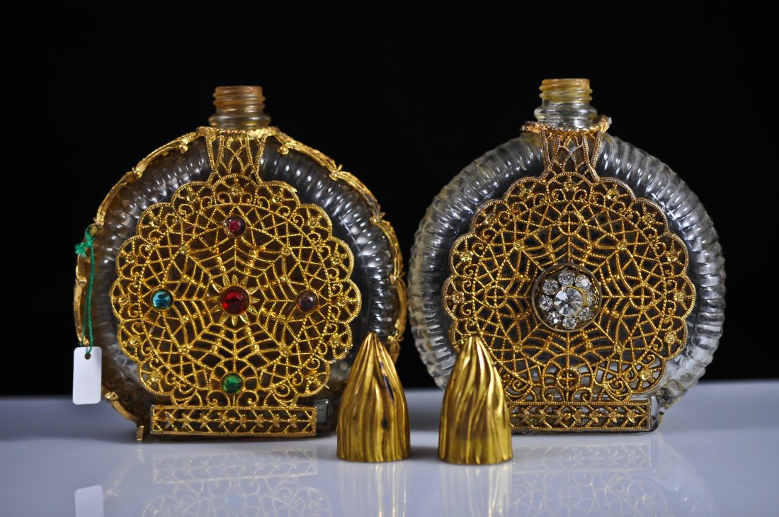 Pair of matching French multi stone perfume bottles: DESCRIPTION: Pair of matching french brass over glass perfume bottle. Ribbed glass design wrapped in ornate brass coverings. First bottle has five encrusted multi colored stones on the front side, the