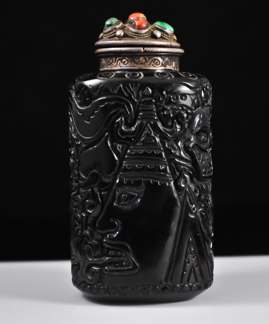Large Chinese carved amber and multi stone snuff bo: DESCRIPTION: Large Chinese amber snuff bottle. Hand carved with skulls and fire breathing figures. Features a silver top (Tested silver) with a copper sheet and seven multi colored stones (Turquoise, 