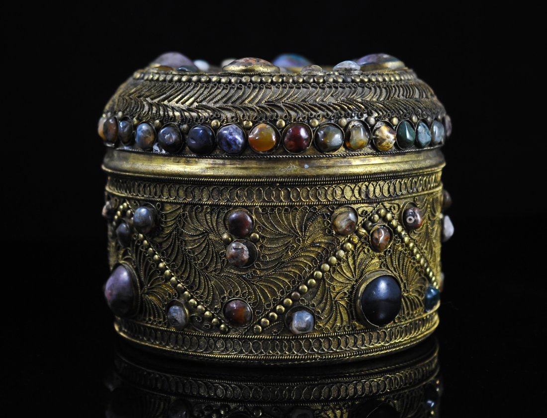 Antique Burmese brass multi colored stone box: DESCRIPTION: Antique Burmese brass box. Hand done filigree design over the whole piece. Bezel set multi colored stones cover the entire box. Missing three small stones. Gorgeous symmetry CIRCA: Early 