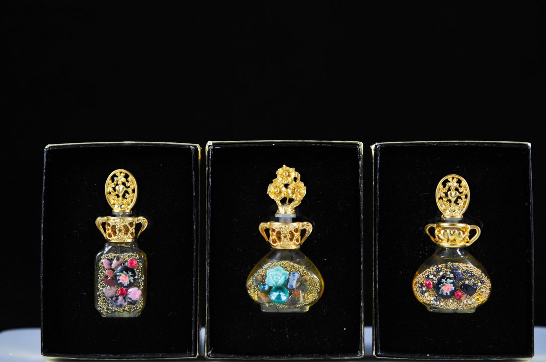 Set of three rare "Adrian Designs" multi stone per: DESCRIPTION: Three bottles of "Adrian Designs" perfume. Features a multi stone design on each one with gold tone overlay. Each one has it's original box. All bottles are full. 3.7 ml CIRCA: Mid to lat