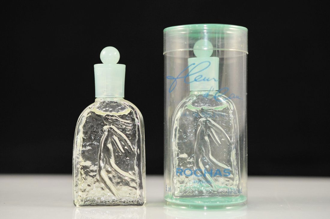 Two miniature bottles of Fleur d'Eau Perfume by Ro: DESCRIPTION: Pair of Fleur d'Eau perfume bottles by Rochas. Both bottles are full with the same scent. One has the original box. 5ml CIRCA: Mid to late 1900's ORIGIN: France DIMENSIONS: H: 2.50"
