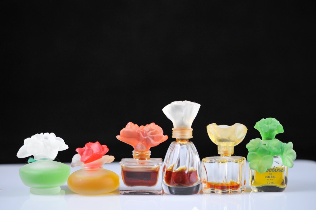 Set of six vintage floral design inspired mini per: DESCRIPTION: Set of six vintage floral designed perfume bottles. Each one is a different brand. All of them feature multi colored floral stoppers. Some bottles are full, some are not. Collectors bottl