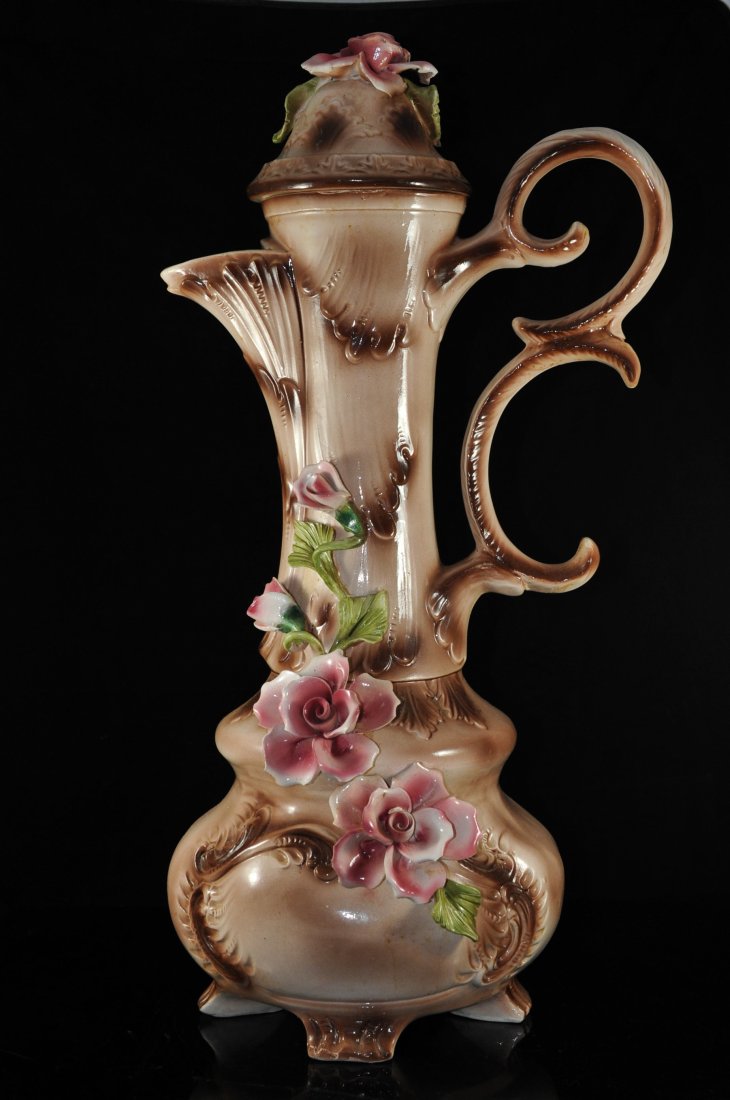 Large Capodimonte porcelain decorative floral pitc: DESCRIPTION: Large decorative Capodimonte pitcher with topper. Footed base design with raised porcelain flowers and leaves. Two tone crimson and pink base color. Small chip on flower pedal. Signed "Ca