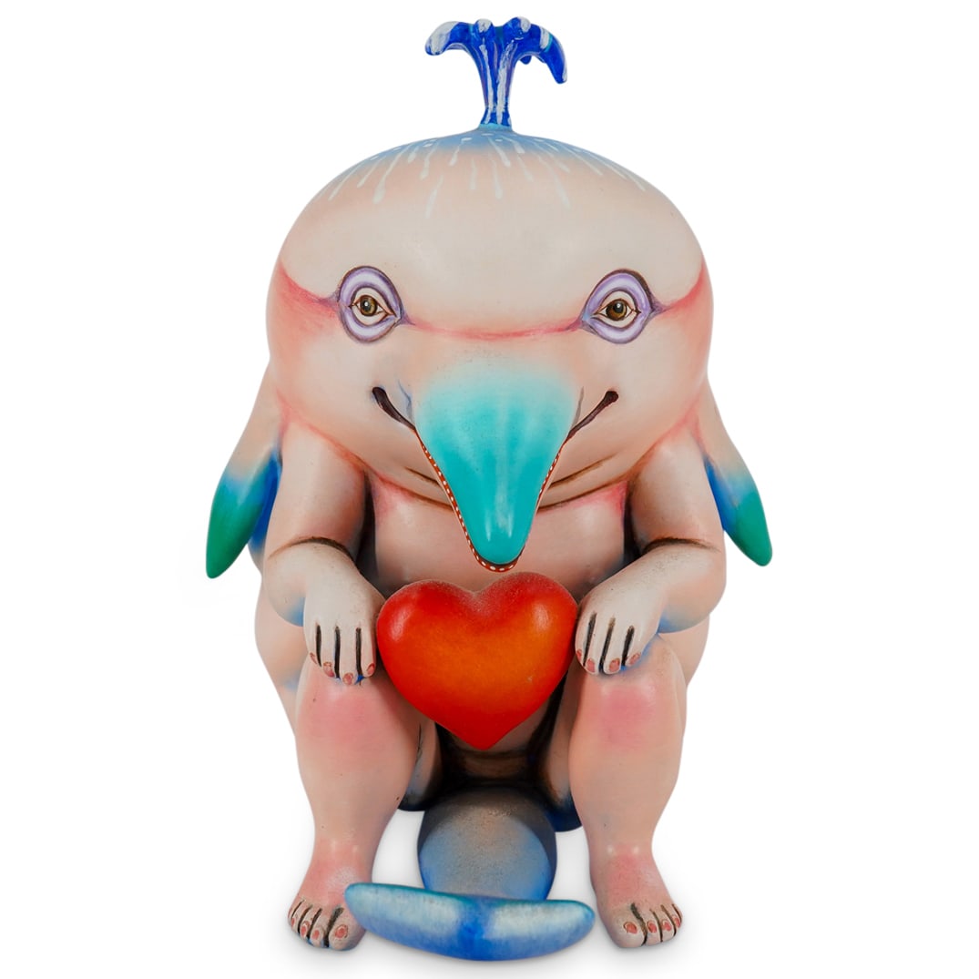 Sergio Bustamante (Mexican, B. 1949) Resin Dolphin Man W/ Heart: DESCRIPTION: Resin figurine by Sergio Bustamante depicting an anthropomorphic dolphin seated on his haunches with a heart between his hands and a spout of water emitting from his blowhole. Signed on v