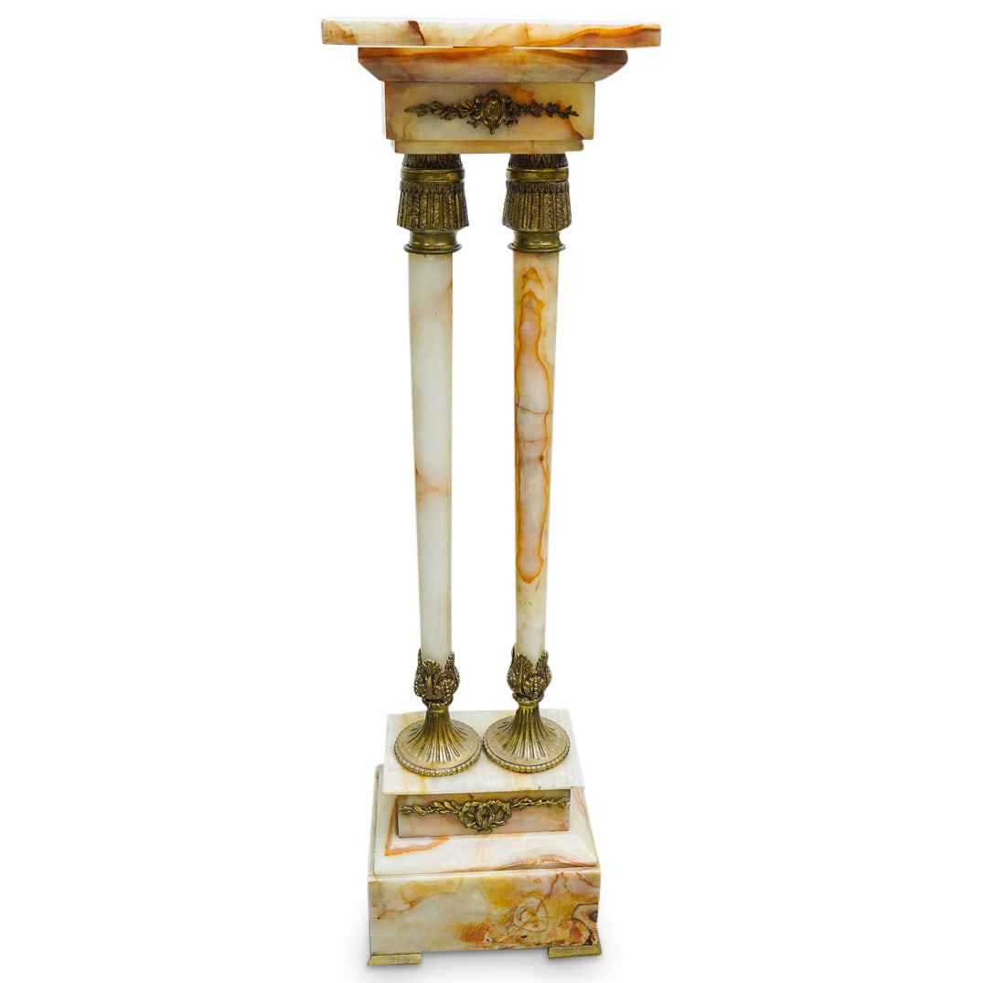 Onyx & Gilt Bronze Pedestal: DESCRIPTION: Onyx & gilt bronze pedestal, the onyx top supported by two onyx columns, each end of each column featuring a gilt bronze fitting decorated with foliage motifs, the columns mounted to an o