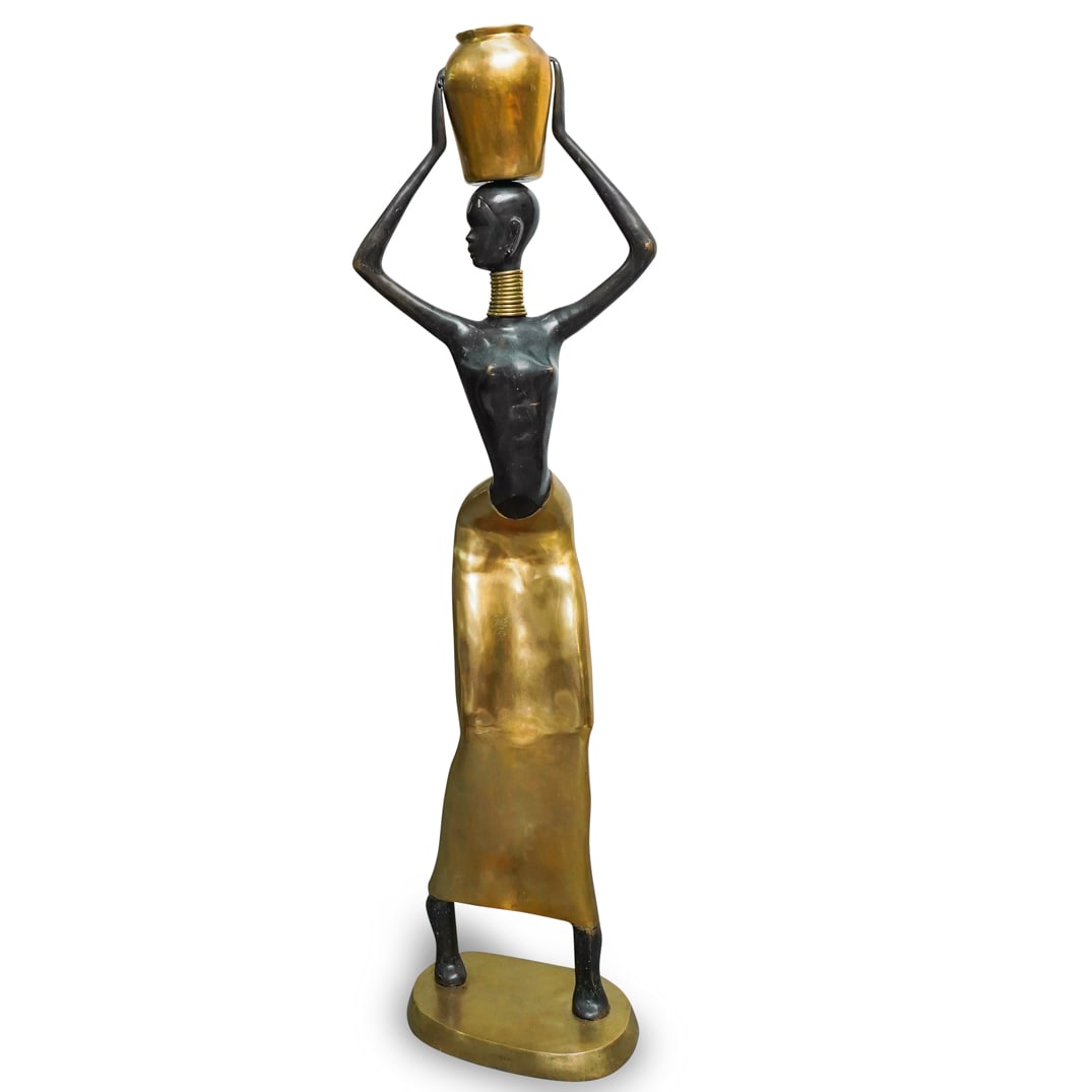 Life Size African Woman Statue Nubian After Karl Hagenauer: DESCRIPTION: Life Size African woman statue depicting a sensuous Nubian female figure, with curved torso, holding a vase over her head. After Karl Hagenauer. With black and gilt patina finish. Karl Ha