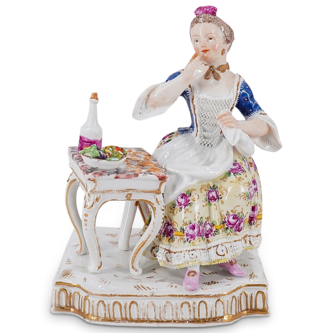 Antique Meissen Porcelain Woman At Sweets Table Figurine: DESCRIPTION: Antique porcelain figurine depicting a woman in lace-hemmed clothing seated at a table sampling sweets on a gilt accented base. CIRCA: 1880s-1920s ORIGIN: Germany DIMENSIONS: H: 5.25" W: 