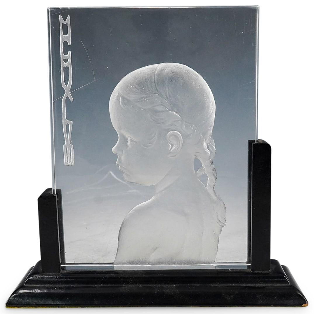 Steuben Glass Relief Child Plaque: DESCRIPTION: Steuben glass relief plaque of a young girl's profile, her hair is in braids. "MCMXIVM" going down the left side. Sits in fitted black wood base. Unsigned CIRCA: 20th Century ORIGIN: Amer