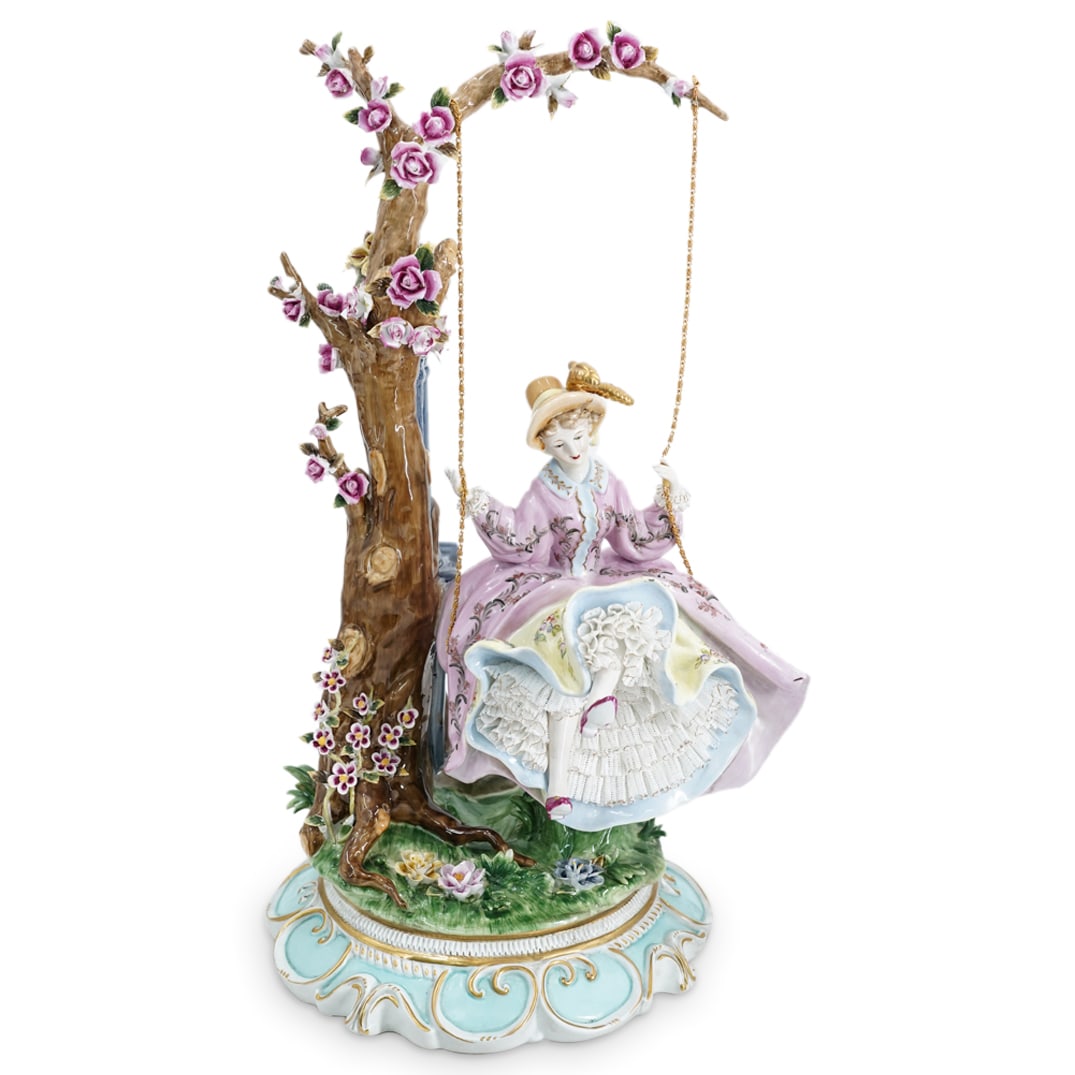 Dresden Woman on Swing Porcelain Group: DESCRIPTION: A Dresden porcelain group, depicting a woman dressed in an 18th century gown sitting on a swing attached to a large porcelain tree by gilt chains. Molded florals throughout entire piece. 