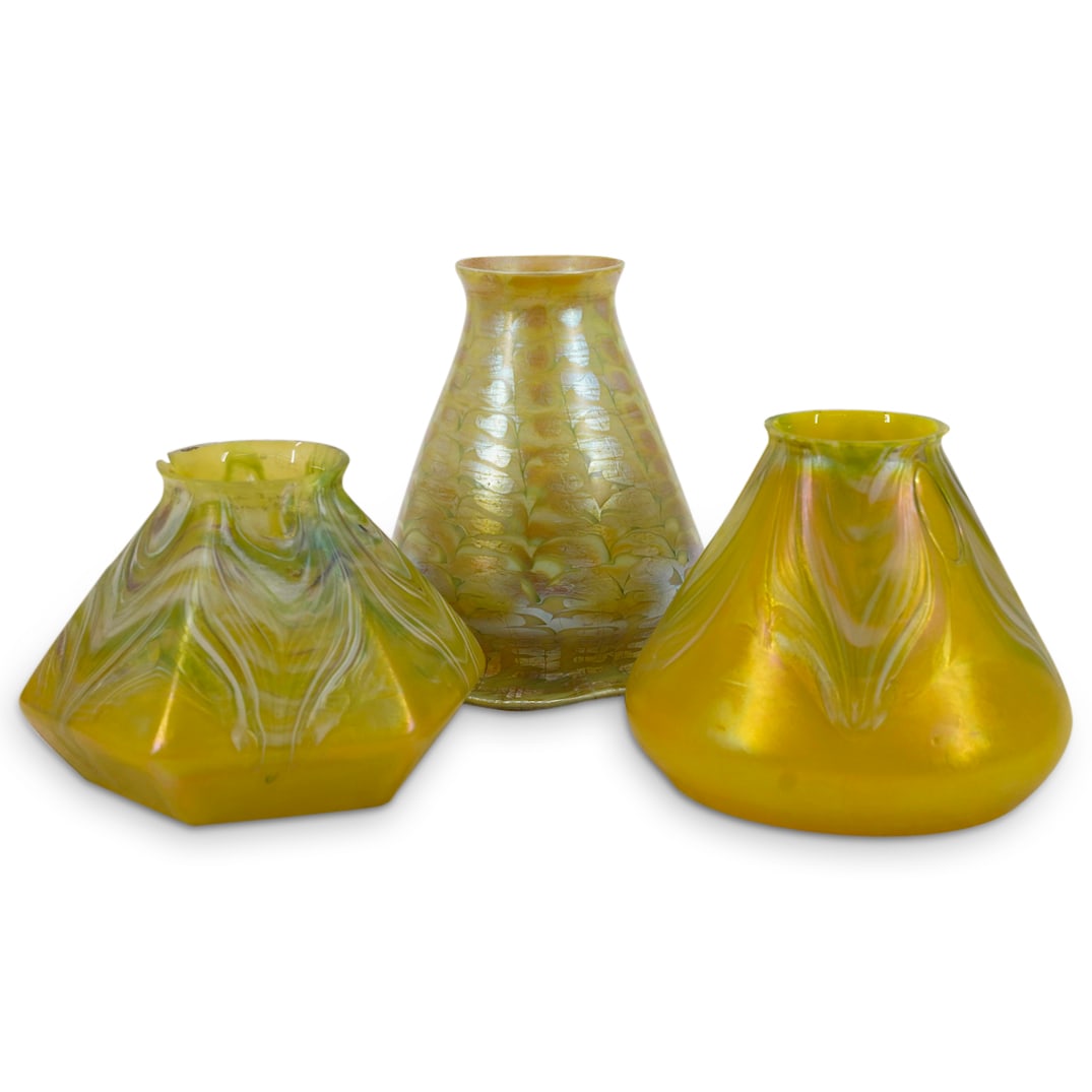 (3 Pc) Loetz Iridescent Art Glass Lamp Shades: DESCRIPTION: Set of 3 Loetz yellow iridescent art glass lamp shades, two with pulled feather design, one with snake skin design. CIRCA: Early 20th Century ORIGIN: Austria DIMENSIONS: H: 5.75" W: 4.75"
