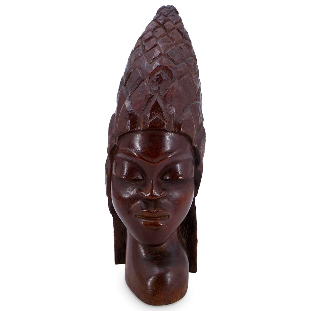 African Carved Wooden Bust: DESCRIPTION: African carved wood bust depicting a woman wearing a pointed headdress.CIRCA: Mid 20th centuryORIGIN: AfricanDIMENSIONS: H: 19" W: 6.5" L: 9"CONDITION: Chipping and age-related crack. Som
