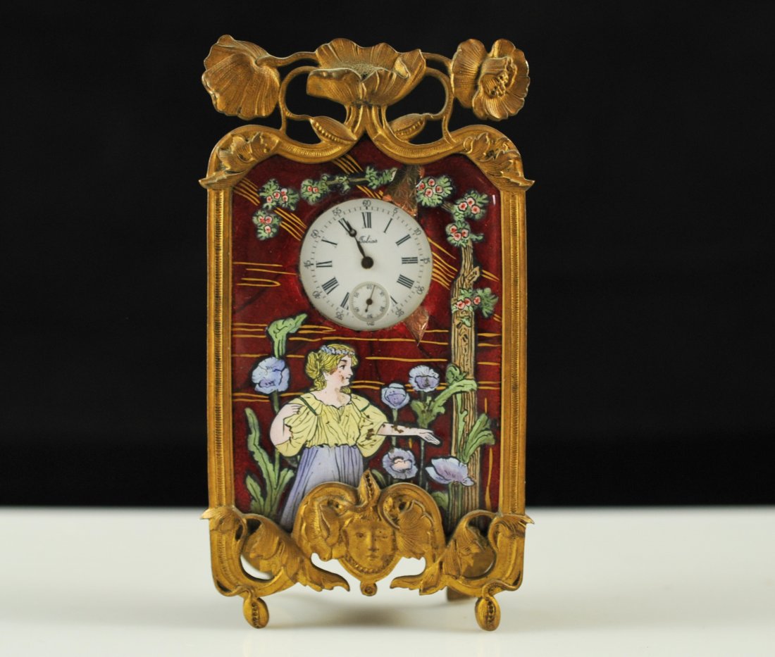Antique bronze and enamel hand painted clock: DESCRIPTION: Antique hand painted enamel and bronze clock. Bronze case with a a top floral motif and a single face towards the base. The front has a hand painted enamel scene of a woman surrounded by 