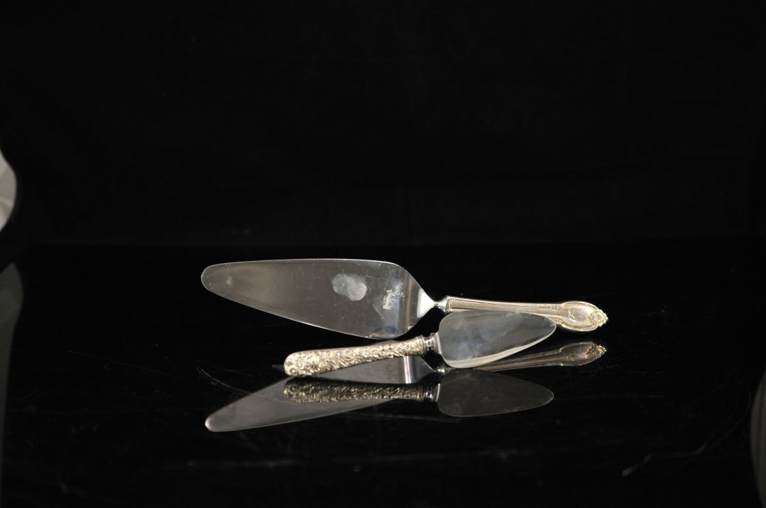 Pair of antique sterling baroque cake servers: DESCRIPTION: Pair of antique sterling baroque cake servers. Smaller piece has heavy baroque floral designs on handle. Large serving piece has a simple elegant floral design as well. 156.4 grams CIRCA: