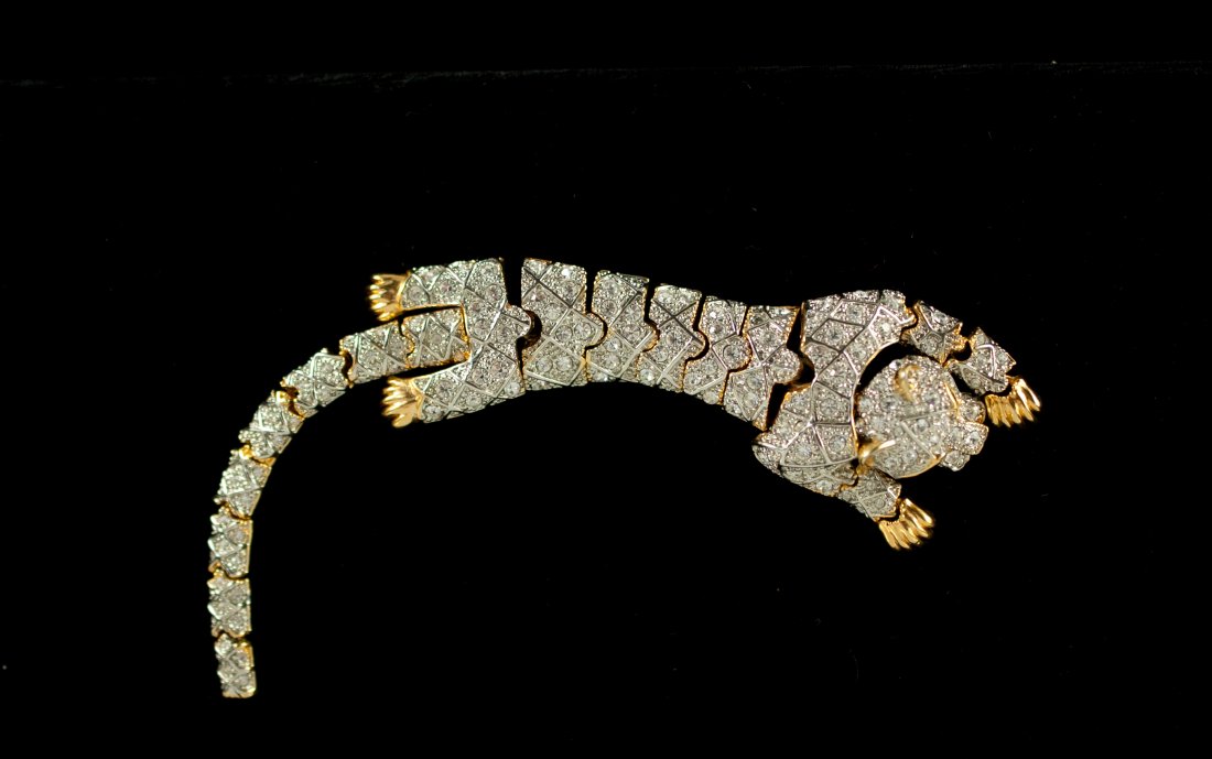 Large designer mechanical panther brooch: DESCRIPTION: Large designer mechanical panther brooch. Extremely ornate, flashy and intricate. Gold and silver tone panther covered in rhinestones with green stone eyes. Each part of the body swivels 