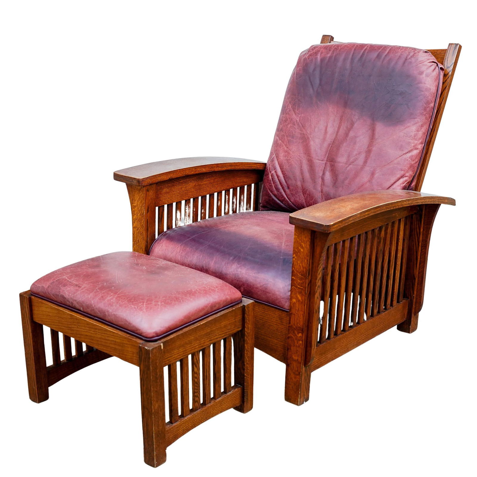 Arts & Crafts Oak Armchair & Ottoman: DESCRIPTION: Arts & Crafts carved tiger oak armchair with bowed armrests, leather upholstery, and slatted design. Crafted with adjustable pegs at backrest to elevate or recline and completed with otto
