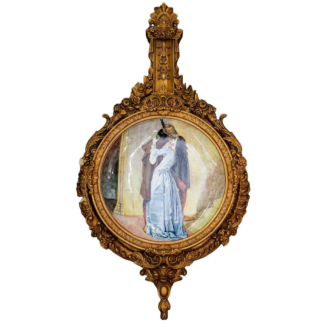 Antique Italian Majolica "Il Bacio" Porcelain Charger In Frame: DESCRIPTION: Antique porcelain charger coated in a majolica glaze depicting "The Kiss" ("Il Bacio") after Francesco Hayez. Mounted in a gilt composite frame sporting flowers and foliage throughout. Ch