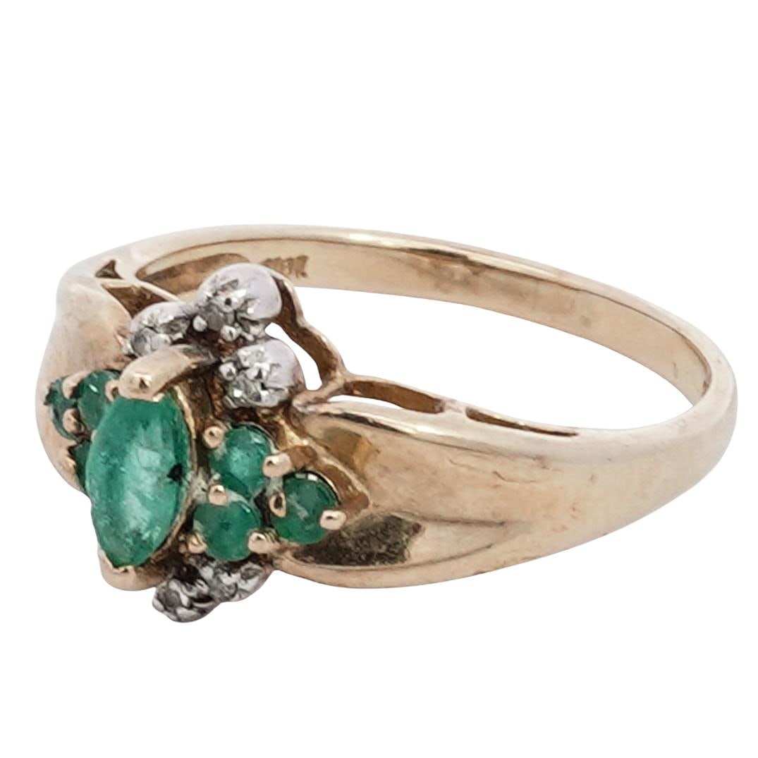 14k Gold, Diamond, and Emerald Ring: DESCRIPTION: 14k gold ring, the central design featuring a marquise cut emerald accented by three round cut emeralds in a triangle cluster. Three small round cut diamonds flanking the top and bottom o