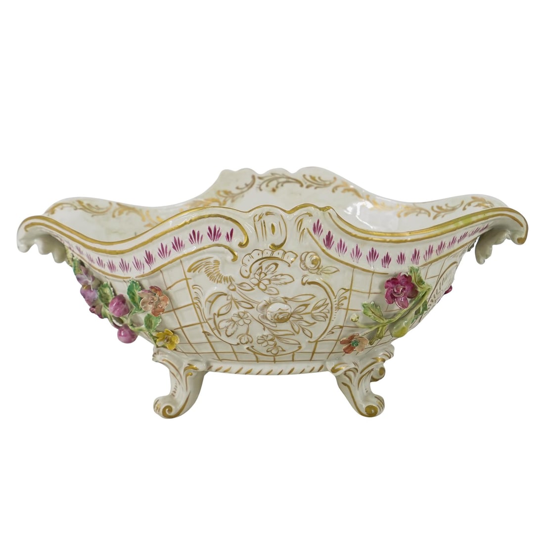 Antique German Porcelain Centerpiece Bowl: DESCRIPTION: Antique centerpiece bowl featuring gilt accenting throughout and floral applications on its exterior flanking low reliefs depicting flowers and foliage. CIRCA: Late 19th to early 20th Cen