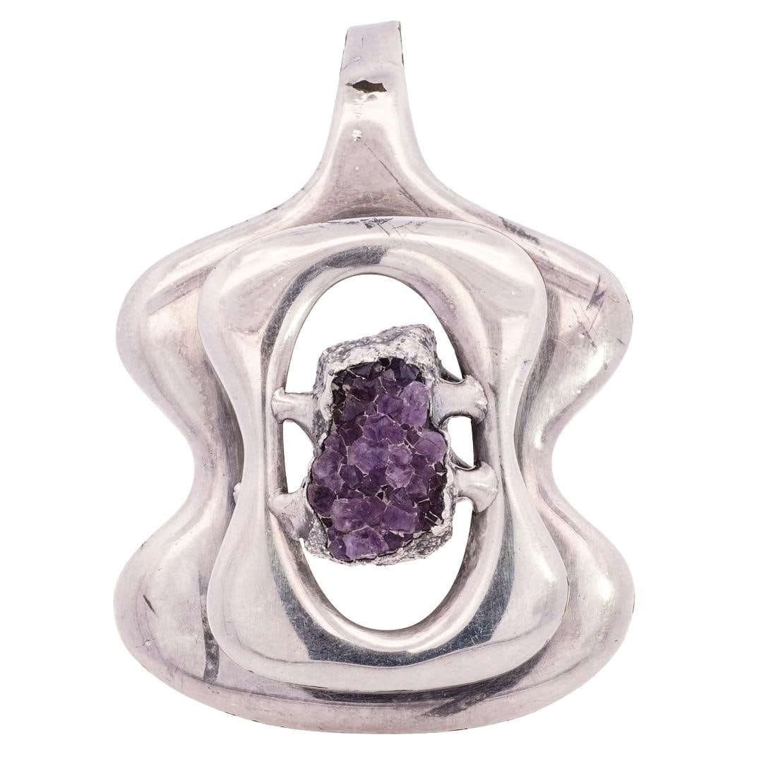 Jacob Hull B & D Silver & Amethyst Pendant: DESCRIPTION: Large silver tone pendant featuring an amethyst centerpiece. Hallmarked "Jacob Hull B & D Denmark" CIRCA: 21st Century ORIGIN: Denmark DIMENSIONS: H: 3" L: 2.25" CONDITION: Normal wear co