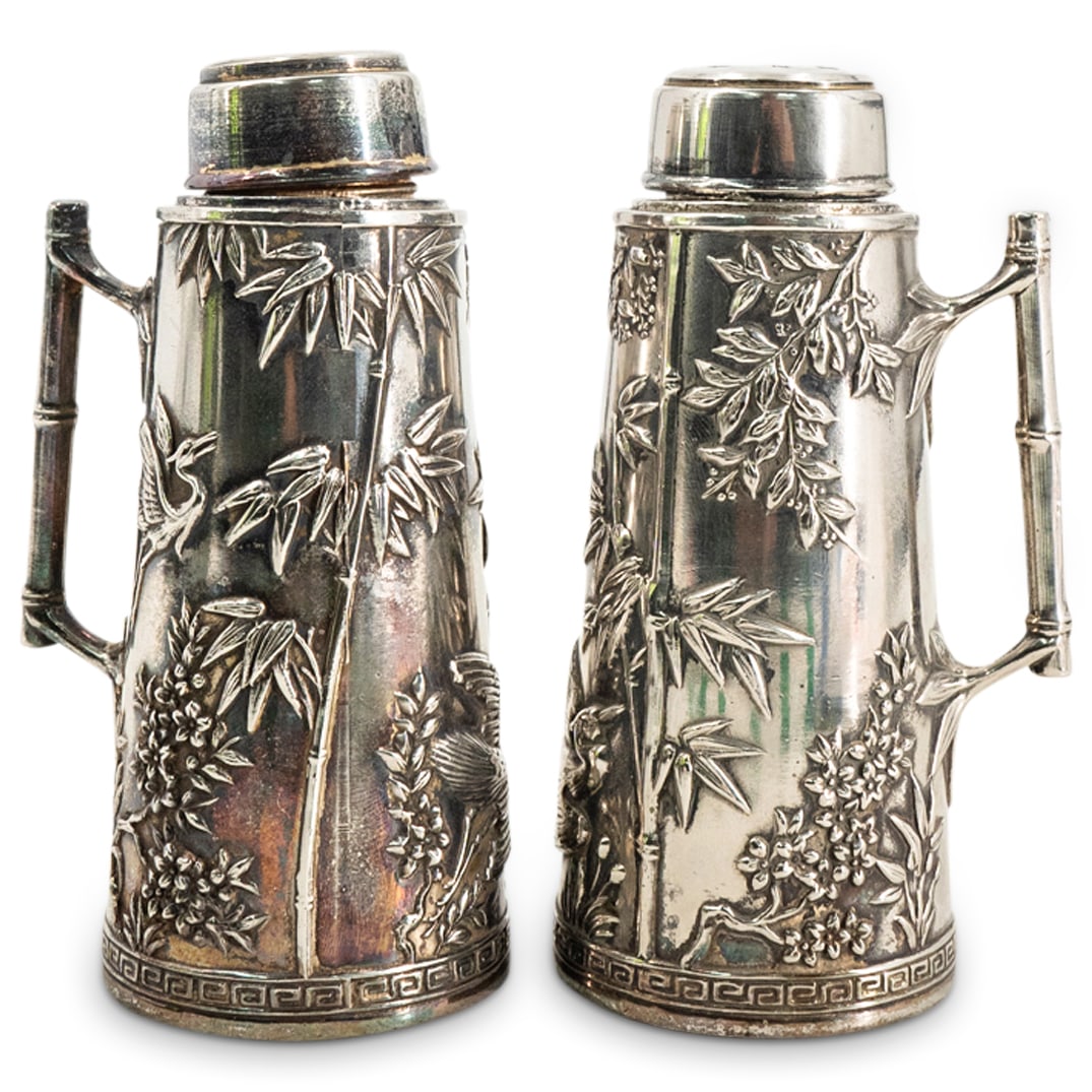 Pair of European Silver Plated Japonisme Shakers: DESCRIPTION: Two matching silver-plated japonisme condiment shakers, each featuring bamboo, crane, flower, and foliage reliefs around its body and sporting a bamboo form handle. Makers mark present on