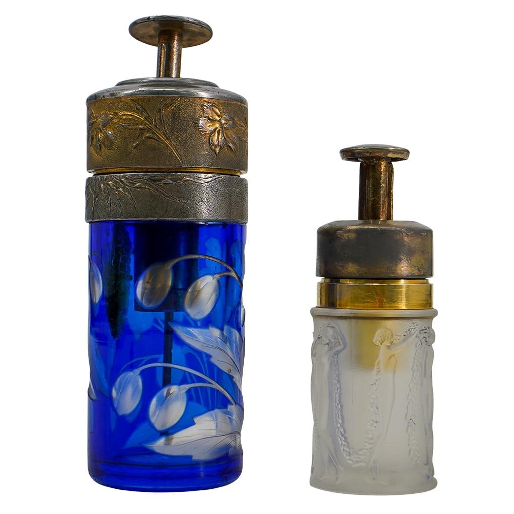 (2 Pc) French Pump Glass Perfume Bottles: DESCRIPTION: Pair of French glass perfume bottles, one cut to blue bottle featuring lilies throughout, with metal topper and engraved Lilies. The small bottle feature nude women in relief throughout. 