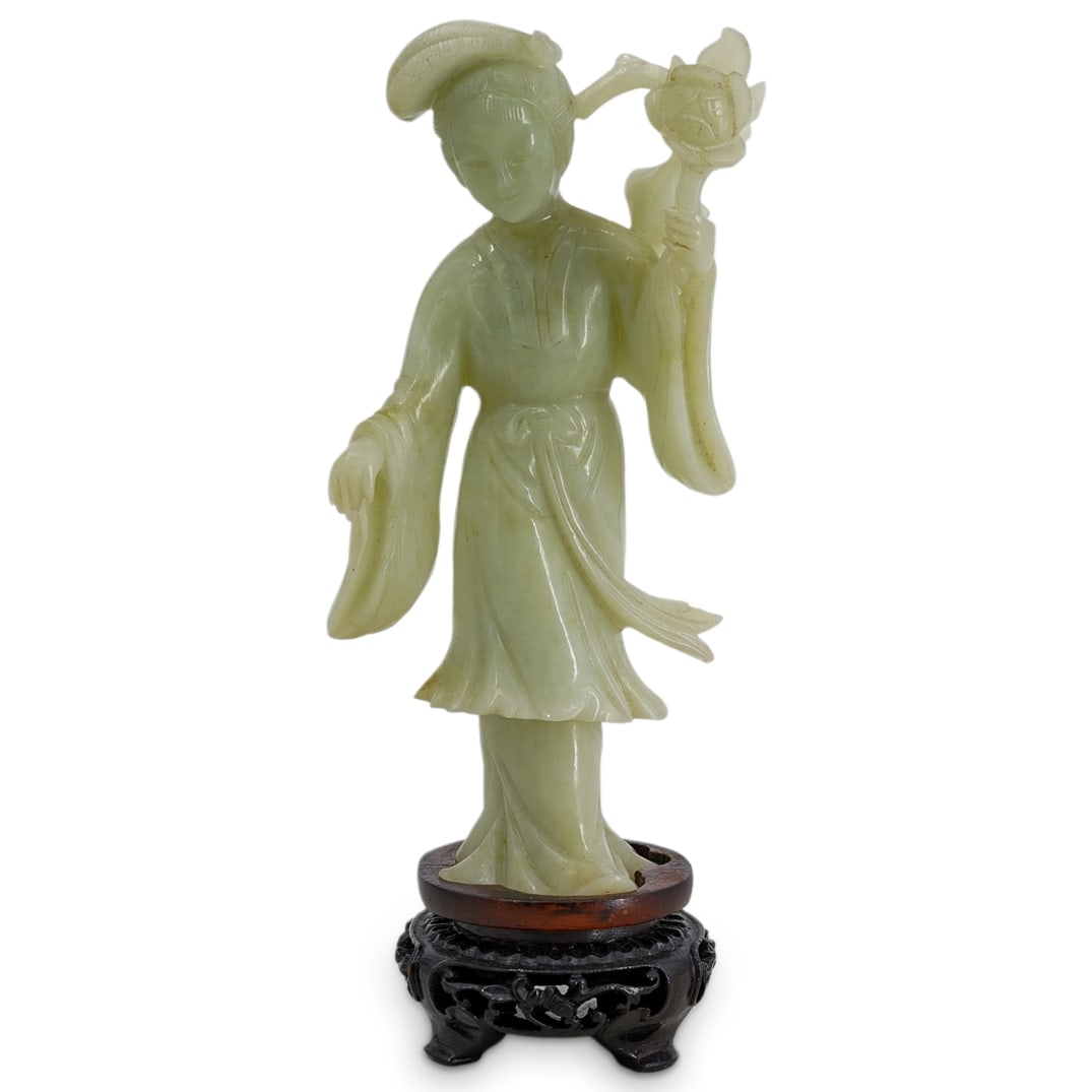 Chinese Carved Jade Woman Figure with Stand: DESCRIPTION: Chinese carved jade figurine, depicting a woman in a long flowing robe, holding a large flower in one hand. Standing atop a carved wood stand. CIRCA: 20th Century ORIGIN: China DIMENSIONS