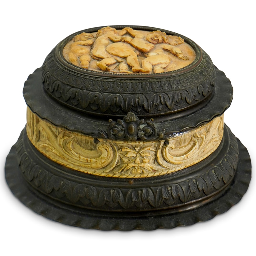 19th C. German Carved Bone & Bronze Box: DESCRIPTION: A 19th Century German hand carved bone inset bronze box, features a round, tiered form with putti relief at top, followed by ornate floral bone carved decoration along body and finished w