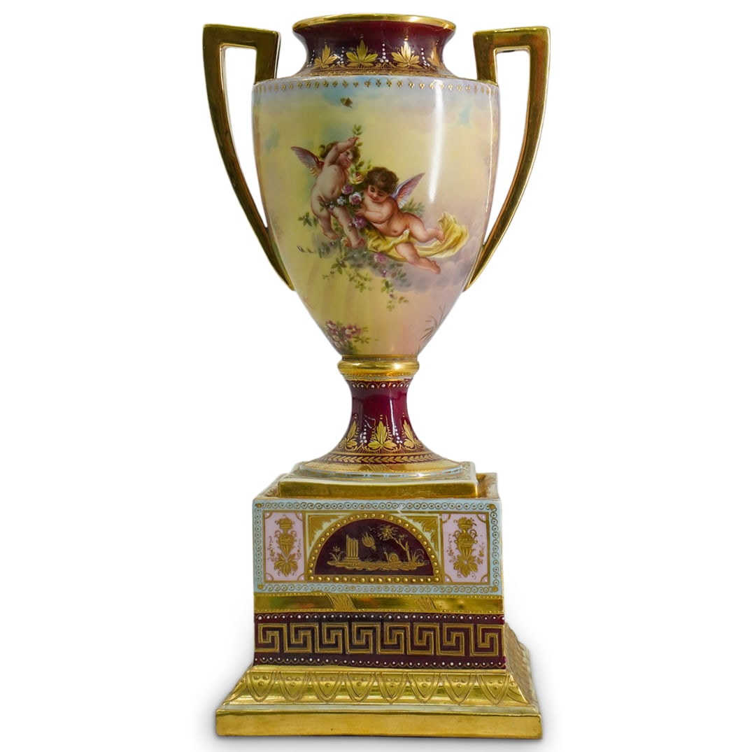 Royal Vienna Hand Painted Porcelain Urn: DESCRIPTION: Royal Vienna hand painted porcelain urn, one side featuring cherubs playing with flowers, the reverse side depicting a romantic couple on a swing. The main body is adorned with a rich bur