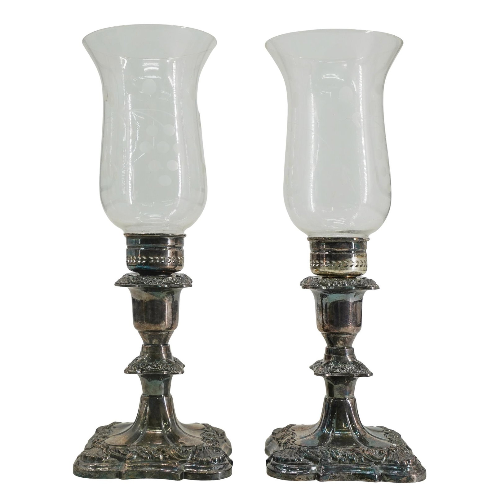 Poole Silver Co. Silver Plated and Glass Candle Holders: DESCRIPTION: Poole Silver Co. Silver Plated candle holders featuring ornate designs, inserted with etched glass hurricanes, stamped along the underside "Old English Poole Silver Co.". CIRCA: 20th Cent