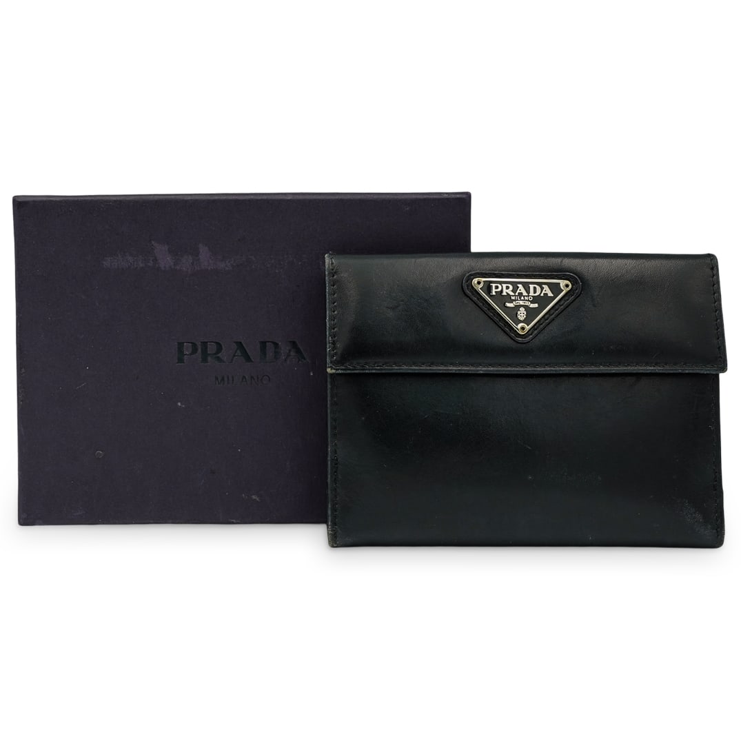 Prada Black Leather Wallet: DESCRIPTION: Prada black leather wallet with logo at front and multiple slot and pocket fold-out design. Includes original box. CIRCA: 20th Cent. ORIGIN: Italy DIMENSIONS: H: 3.75" X L: 4.75" CONDITIO