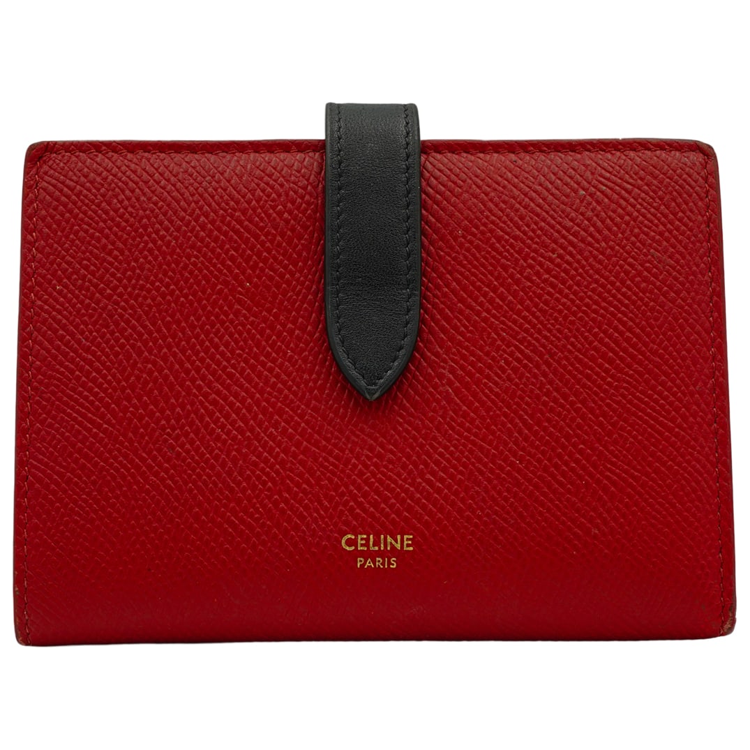 Celine Medium Bi-Fold Strap Wallet: DESCRIPTION: This Celine medium strap wallet is red with a navy blue strip snap closure, has gold tone stamp on front lower center. Interior has gold tone hardware zip closure coin pouch, cash compart