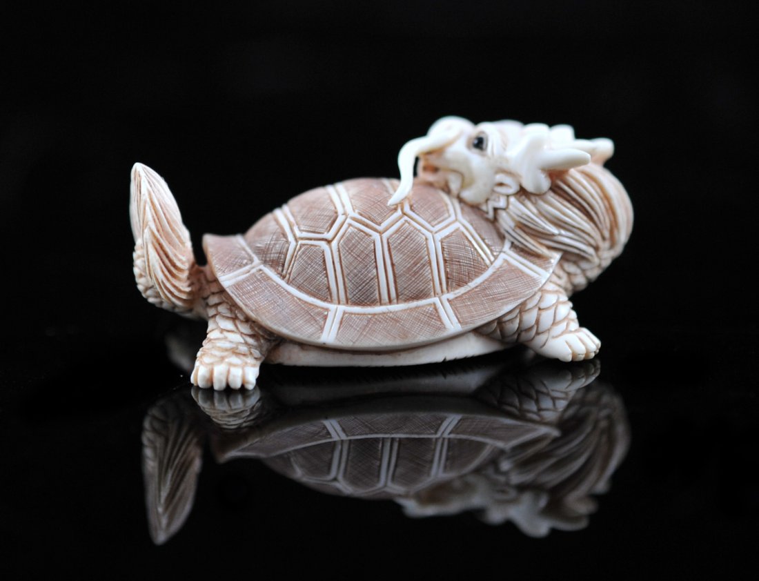 Japanese ivory "dragon turtle" netsuke. Signed: DESCRIPTION: Japanese ivory "dragon turtle" netsuke. Hand carved mythological "Dragon turtle" creature with a crimson polychrome patina. Signed CIRCA: Mid 1900's ORIGIN: Japan DIMENSIONS: H: 0.75" L: 