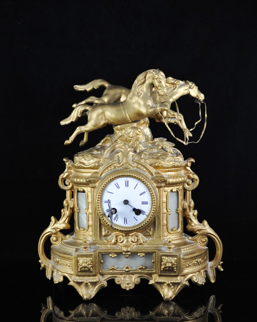 Vintage gilt metal double horse clock: DESCRIPTION: Vintage gilt metal double horse clock. Ornate mantle clock made from white metal with a gold patina. Features two sprinting horses with ground and foliage work underneath. Original pendul