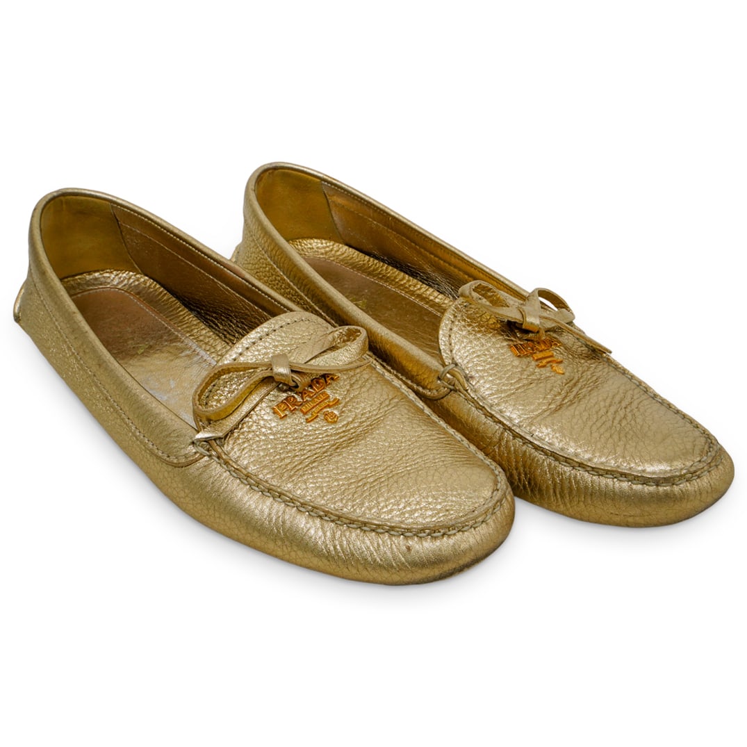 Prada Gold Metallic Leather Loafers - Size 39: DESCRIPTION: Prada Gold metallic leather loafers, with gold tone metal logo, and leather bow. Women's Size: 39 CIRCA: 20th century ORIGIN: Italy DIMENSIONS: Size: 39 CONDITION: Good pre-owned conditio