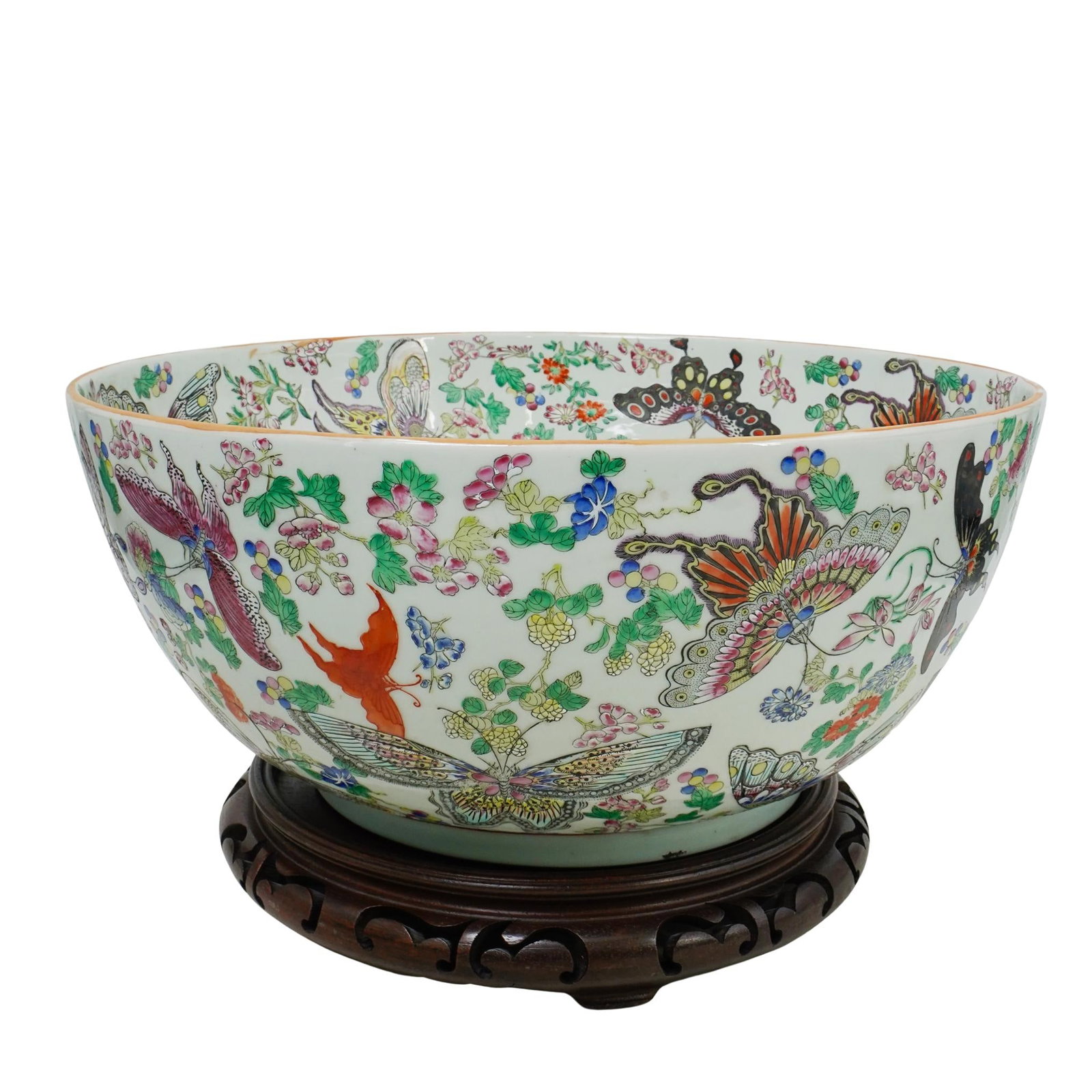 Large Chinese Famille Rose Porcelain Bowl: DESCRIPTION: Large Chinese famille rose porcelain vessel or centerpiece bowl on a wooden base. Depicts floral elements with various patterned butterflies. Base is a carved dark wood. Bowl measures dia