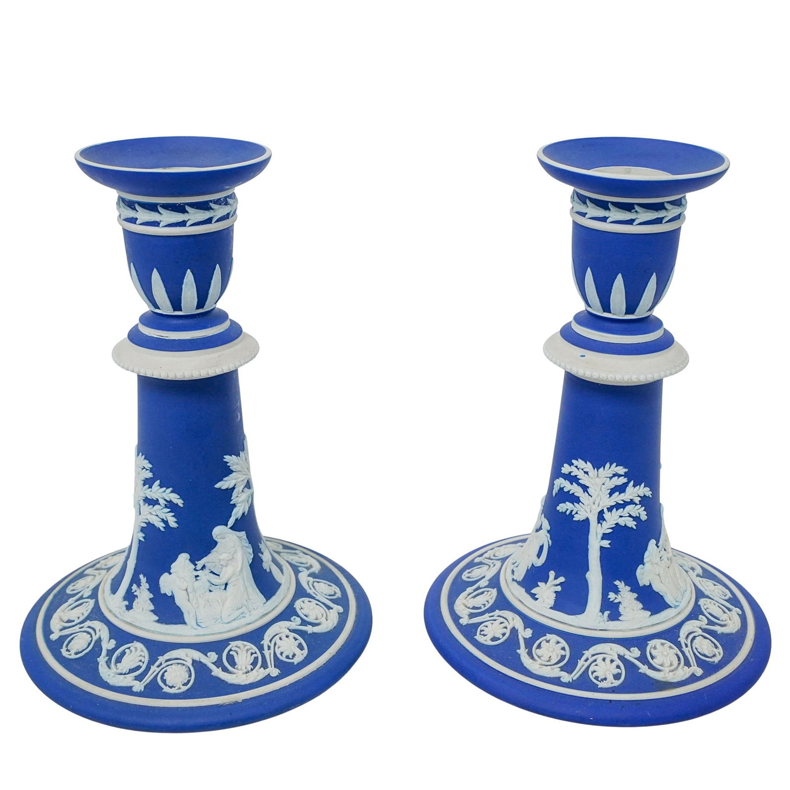 Pair of Wedgwood English Stoneware Candlesticks: DESCRIPTION: A pair of candlesticks made of stoneware with a matte, unglazed finish. They feature a dark blue base with white bas-relief decorations. The candlesticks have a circular base, a slender s