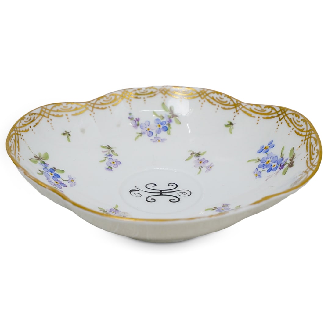 Meissen Germany Porcelain Saucer: DESCRIPTION: Porcelain saucer with a smooth, glossy finish. Delicate hand-painted purple-blue floral motifs. Gold trim along the scalloped edge with intricate detailing. The letter "H" at the center.