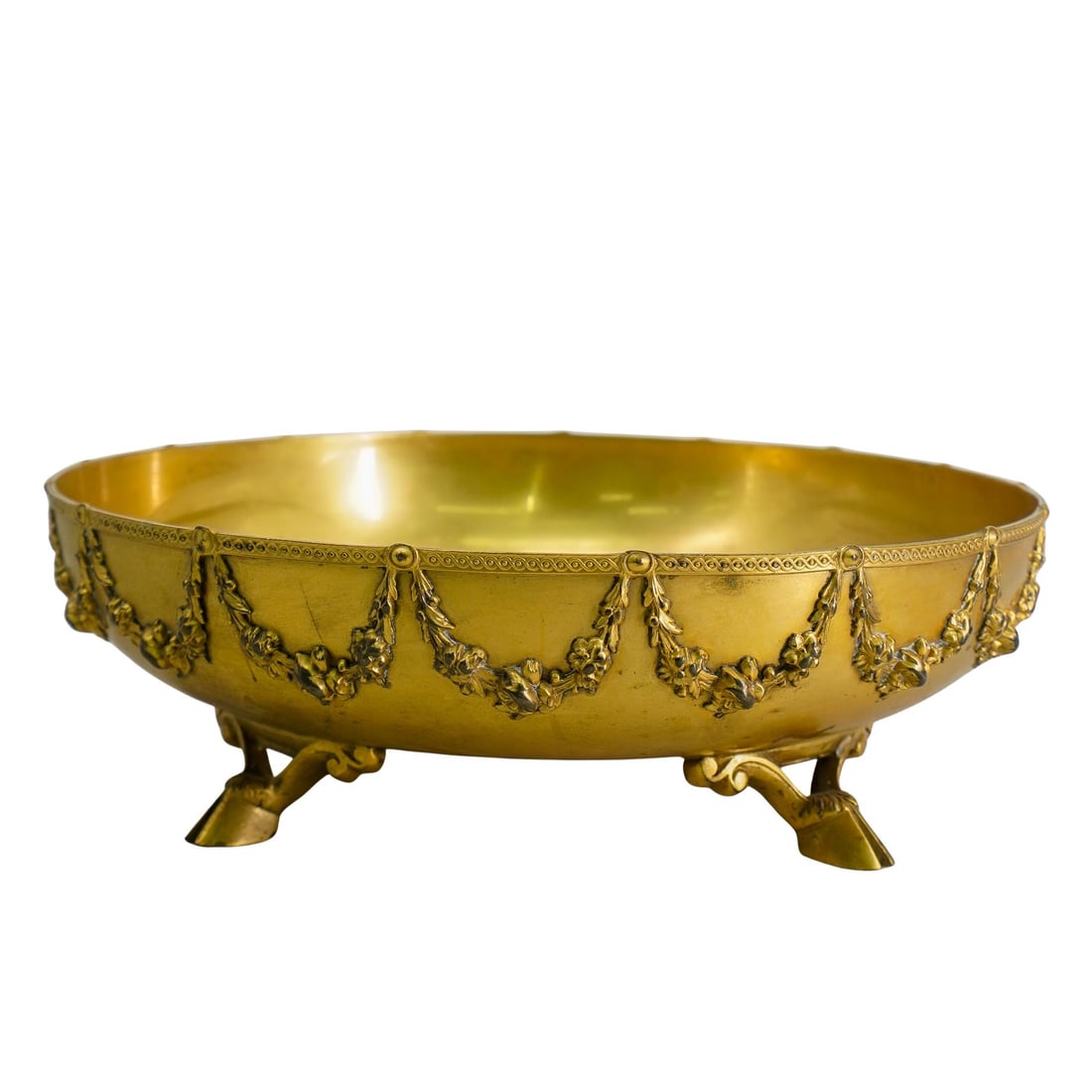 19th C. French Gilt Bronze Centerpiece Bowl: DESCRIPTION: A French gild brown centerpiece bowl with round form, ornate hanging wreath releifs, raised on animalistic hoof feet, completed with interlaced pattern trims. CIRCA: 19th Cent. ORIGIN: Fr
