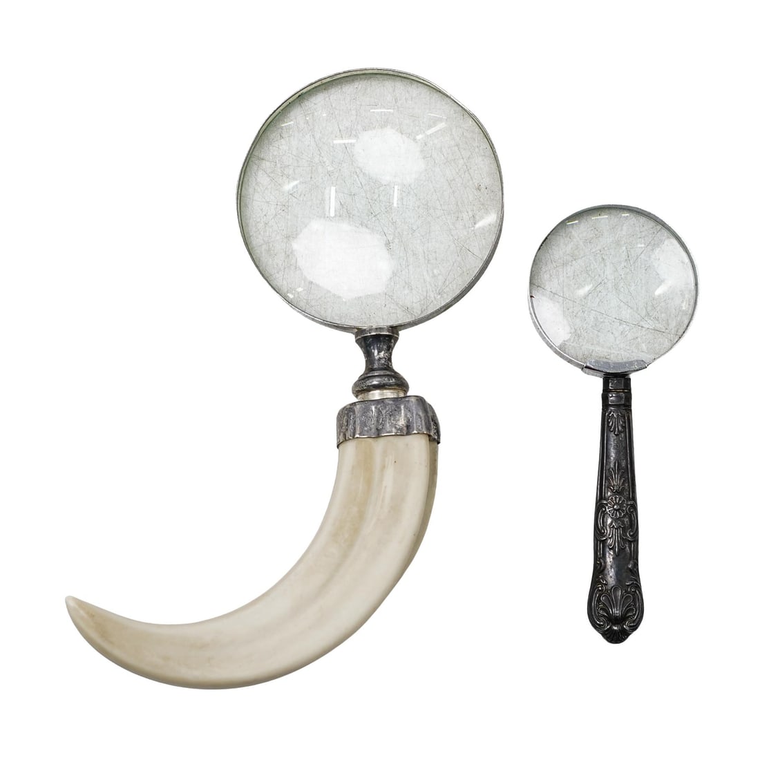 (2 Pc) Vintage Sterling and Tusk Magnifying Glasses: DESCRIPTION: The bigger magnifying glass features a curved handle made of a material resembling cellulose, in the form of a boar tusk. The handle has a smooth, polished finish and a ridged texture. Th