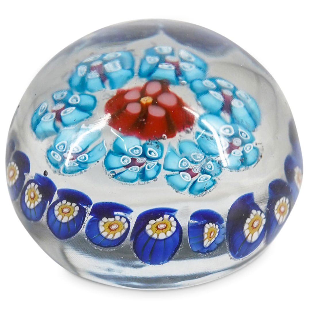 Vintage Millefiori Glass Paperweight: DESCRIPTION: A paperweight featuring a convex, rotund, form embellished with interior scattered millefiori designs along with a cobalt blue base hue along the underside. CIRCA: 20th Century ORIGIN: Co