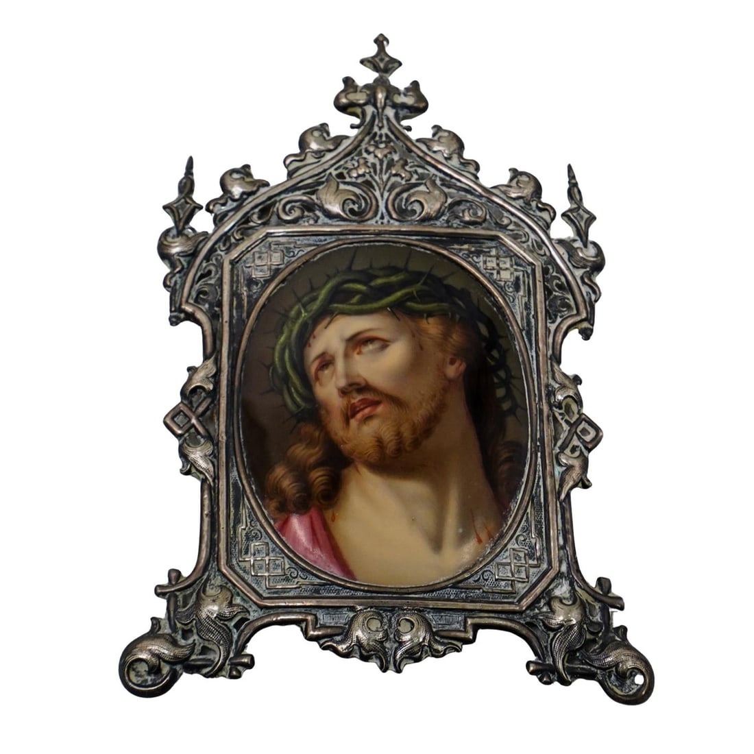 Antique Hand Painted Jesus On Porcelain In Silver Frame: DESCRIPTION: Antique hand painted portrait of Jesus wearing a crown of thorns, on an oval shaped porcelain plaque. The portrait is housed within a silver baroque style frame. CIRCA: Late 19th to Early