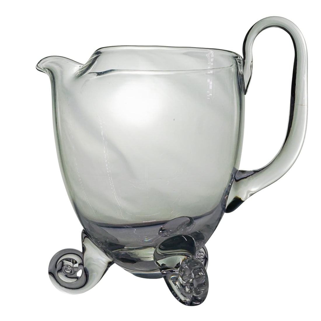 Steuben Style Glass Pitcher: Steuben Style Glass Pitcher20th century, USAHigh-quality, clear glass with a curved handle. The pitcher has a pour spout and scrolled feet. The body is smooth and rounded, giving it a bulbous form tha