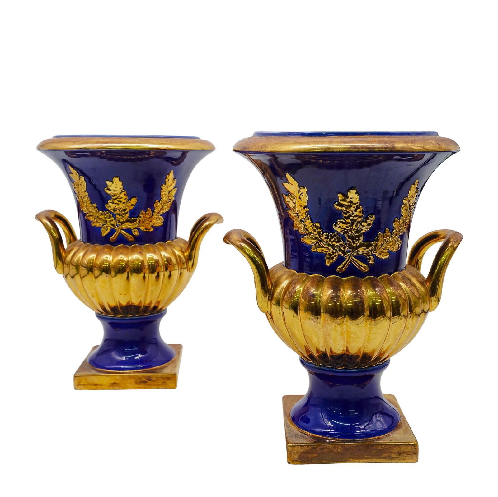 Pair Of French Empire Style Cobalt Porcelain Urns: Pair Of French Empire Style Cobalt Porcelain UrnsEarly 20th Century, FrancePair of French Empire style porcelain urns, featuring a cobalt blue glaze contrasted by bright gilded oak and acorn leaf moti