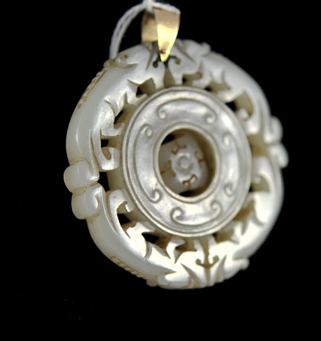 Chinese white jade and 14k mechanical discus pendant: DESCRIPTION: Chinese white jade and 14k mechanical discus pendant. Hand carved white jade pendant featuring four foo dogs which make up the border. The center has a rotating (Luck) discus held in plac