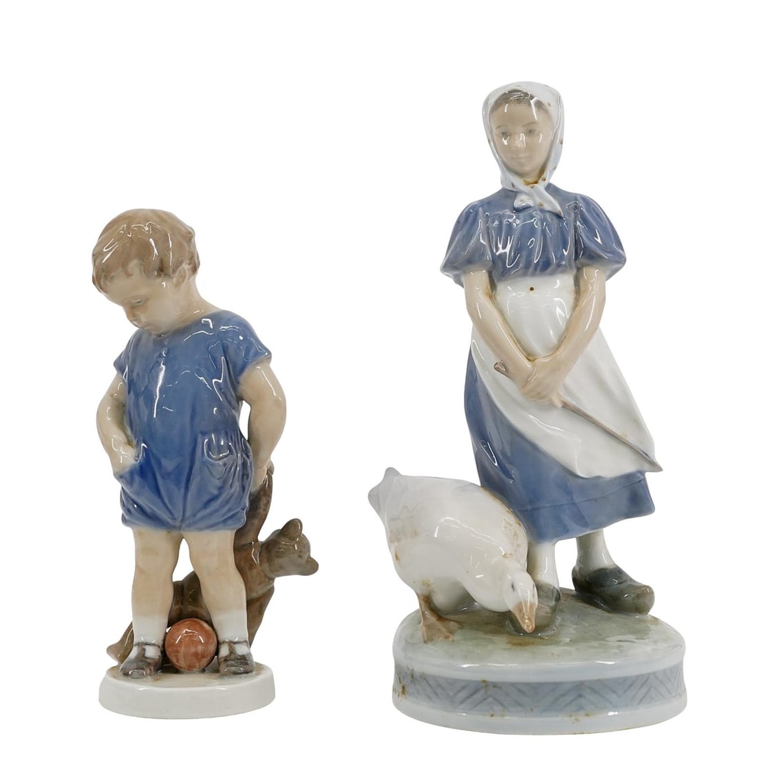 Pair of Royal Copenhagen Porcelain Figurines: Pair of Royal Copenhagen Porcelain Figurines 20th century, Denmark A pair of porcelain figurines: A young boy with a teddy bear and a ball, mounted on a round base. On the underside is: "Royal Copenha