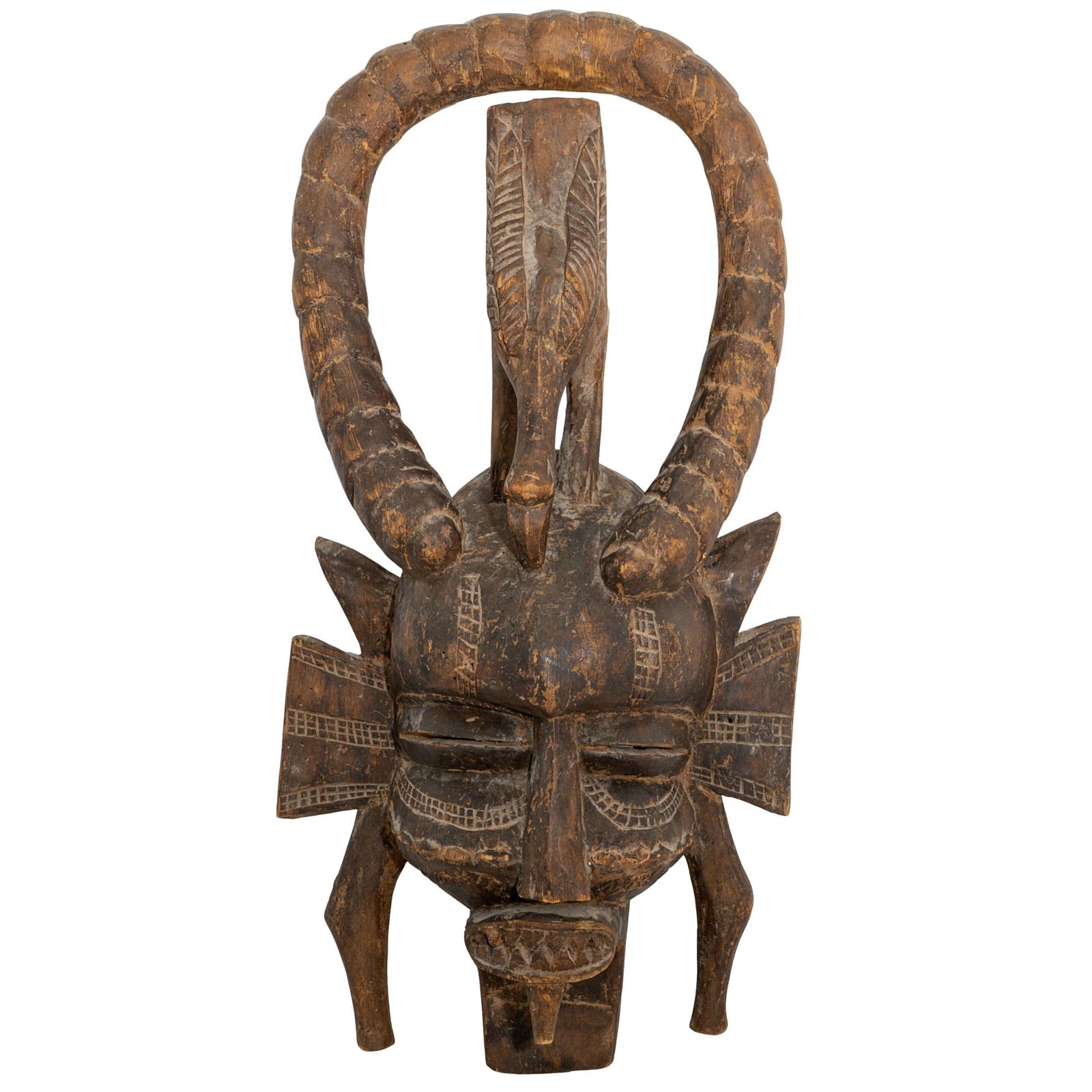 Large Wooden Tribal Mask Sculpture: Large Wooden Tribal Mask Sculpture 20th century, Africa Large carved wooden tribal mask sculpture featuring bold geometric facial features, protruding teeth, and a pair of coiled horns. The piece is m